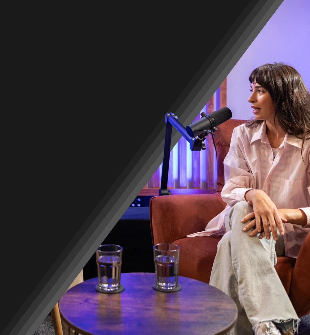 female podcast host sitting next to microphone while recording an episode.