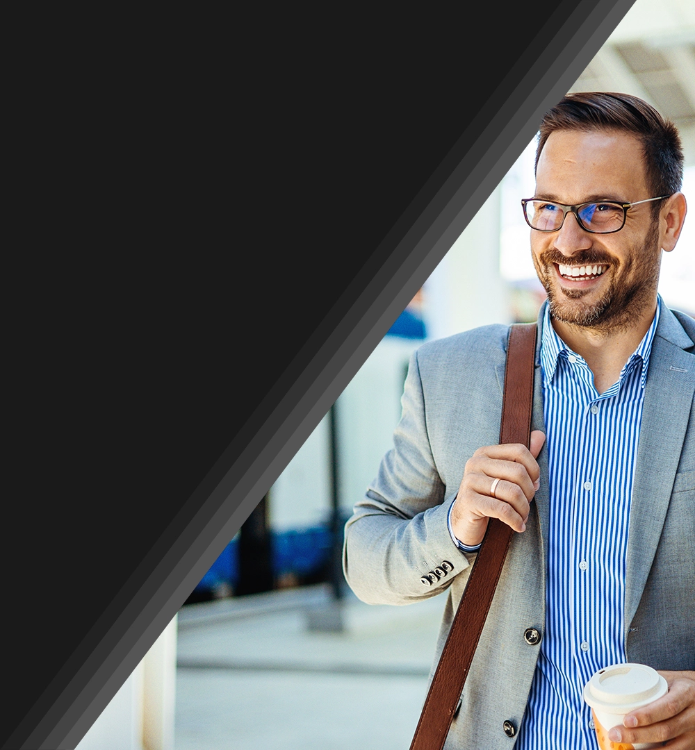 conference attendee walking through hallway with shoulder bag and coffee in hand.